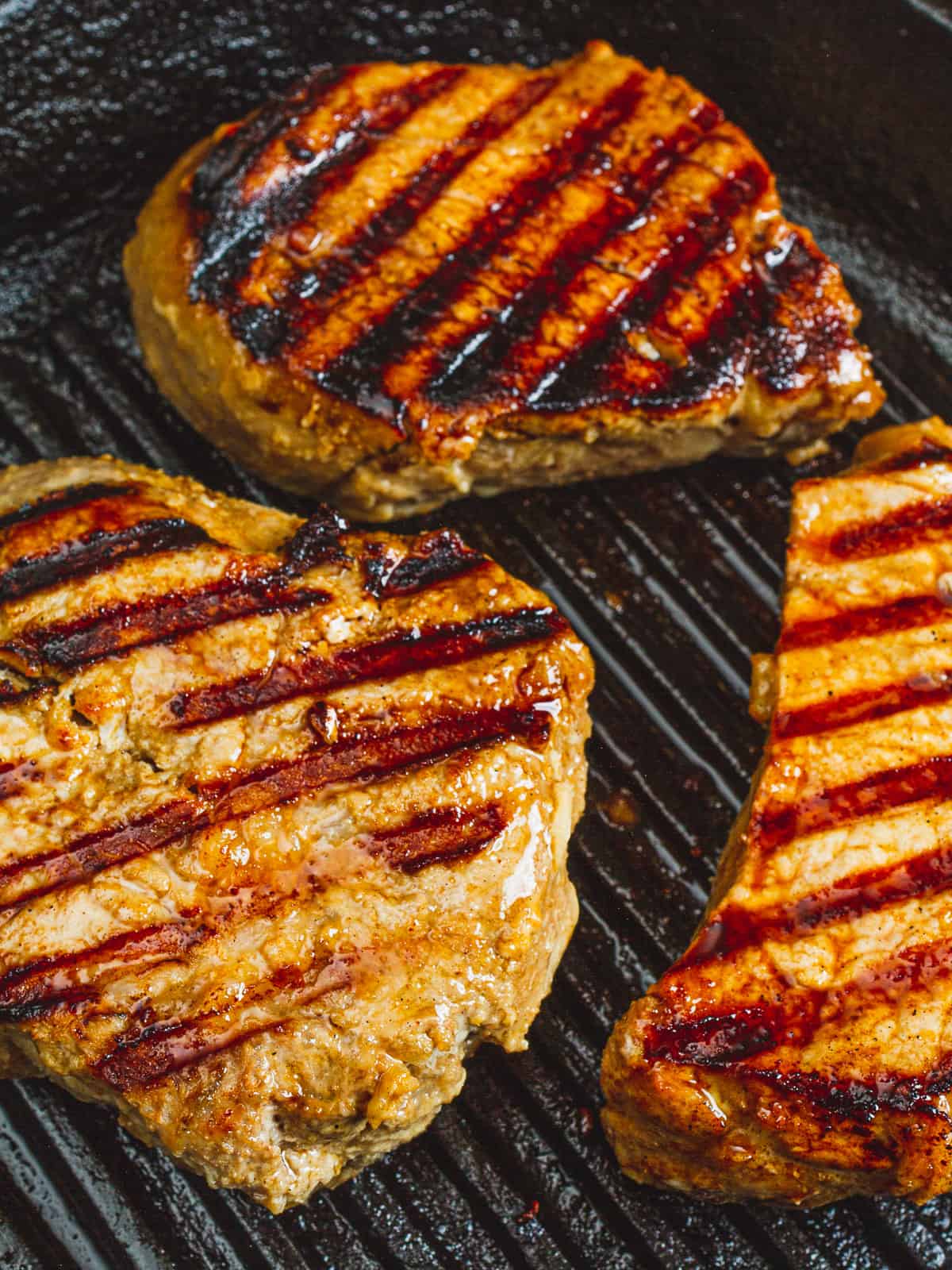 grilled hawaiian pork chops after flipping — you can see distinct grill marks.
