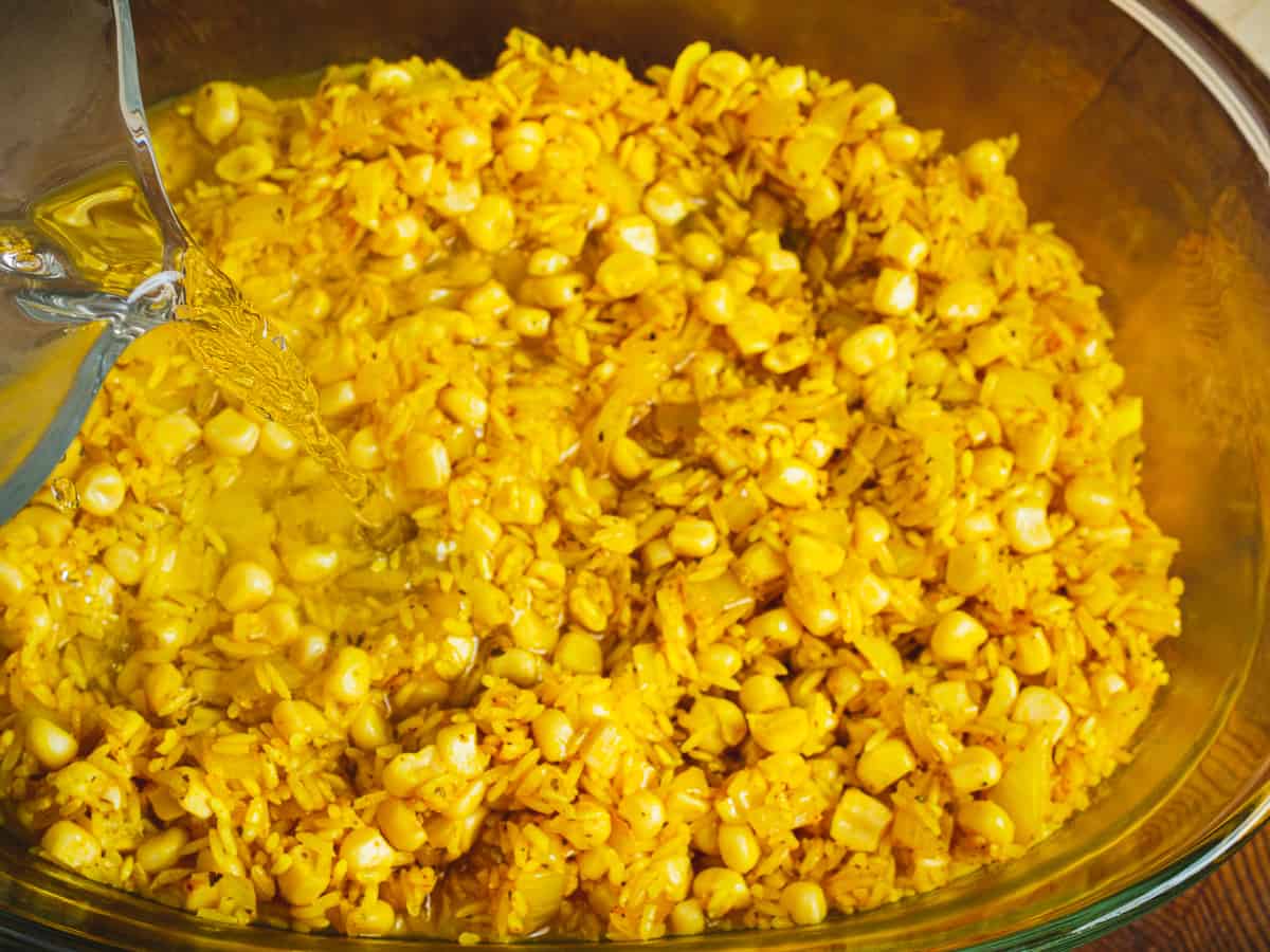adding liquid to the special corn rice in a baking dish.
