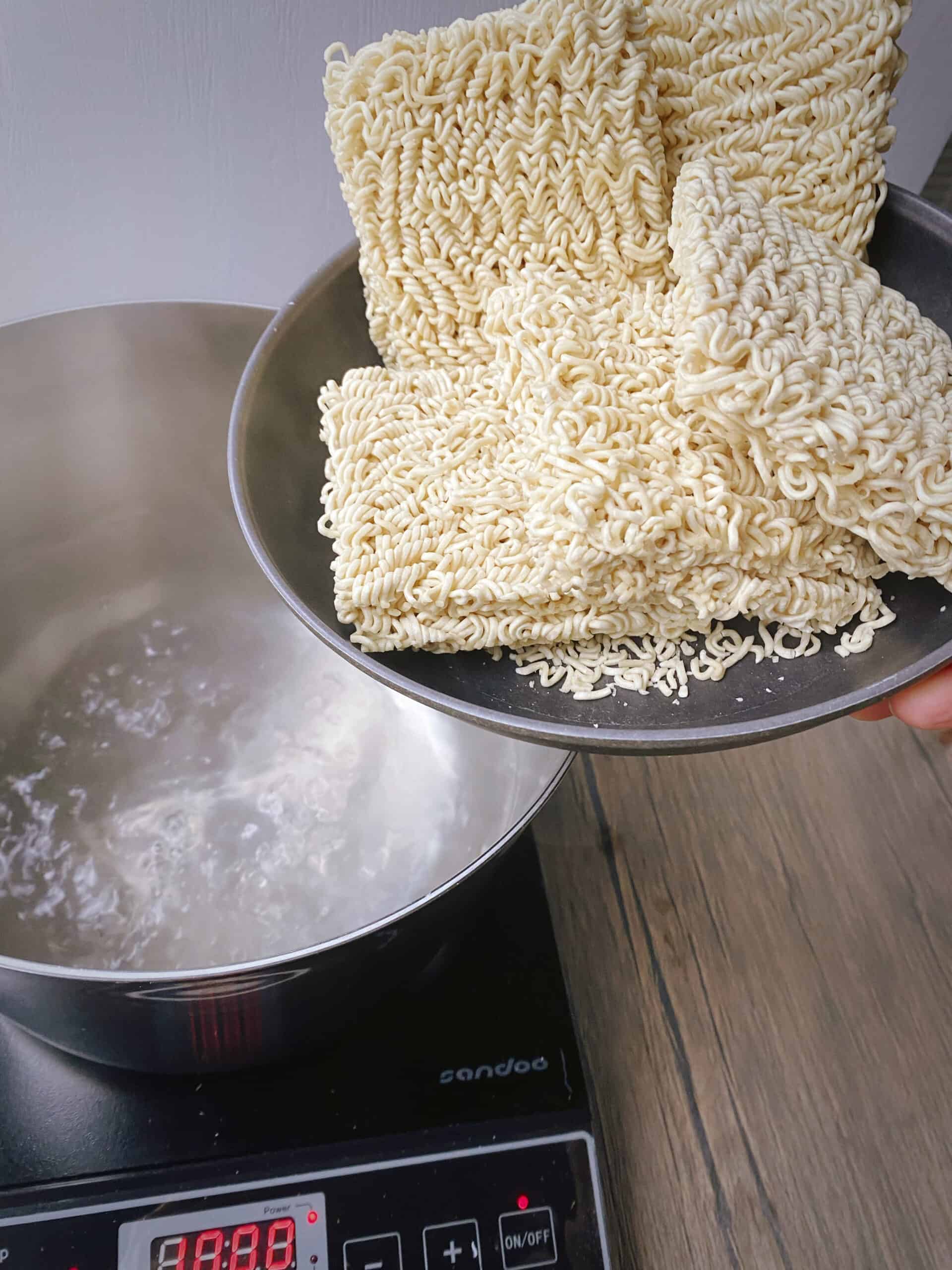 ramen noodles in a bowl about to be added to a pot of boiling water.