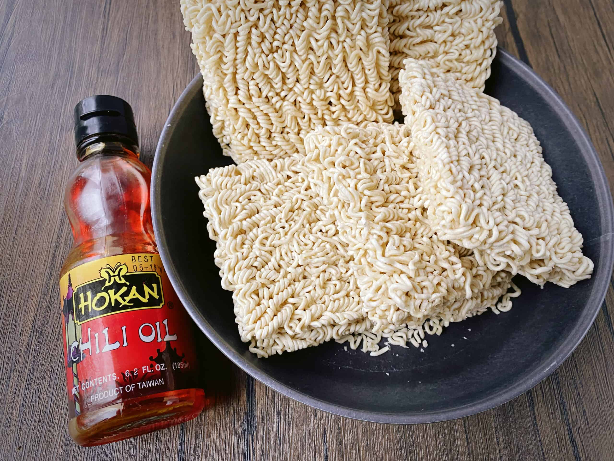 bottle of chili oil next to 5 squares of instant ramen noodles.