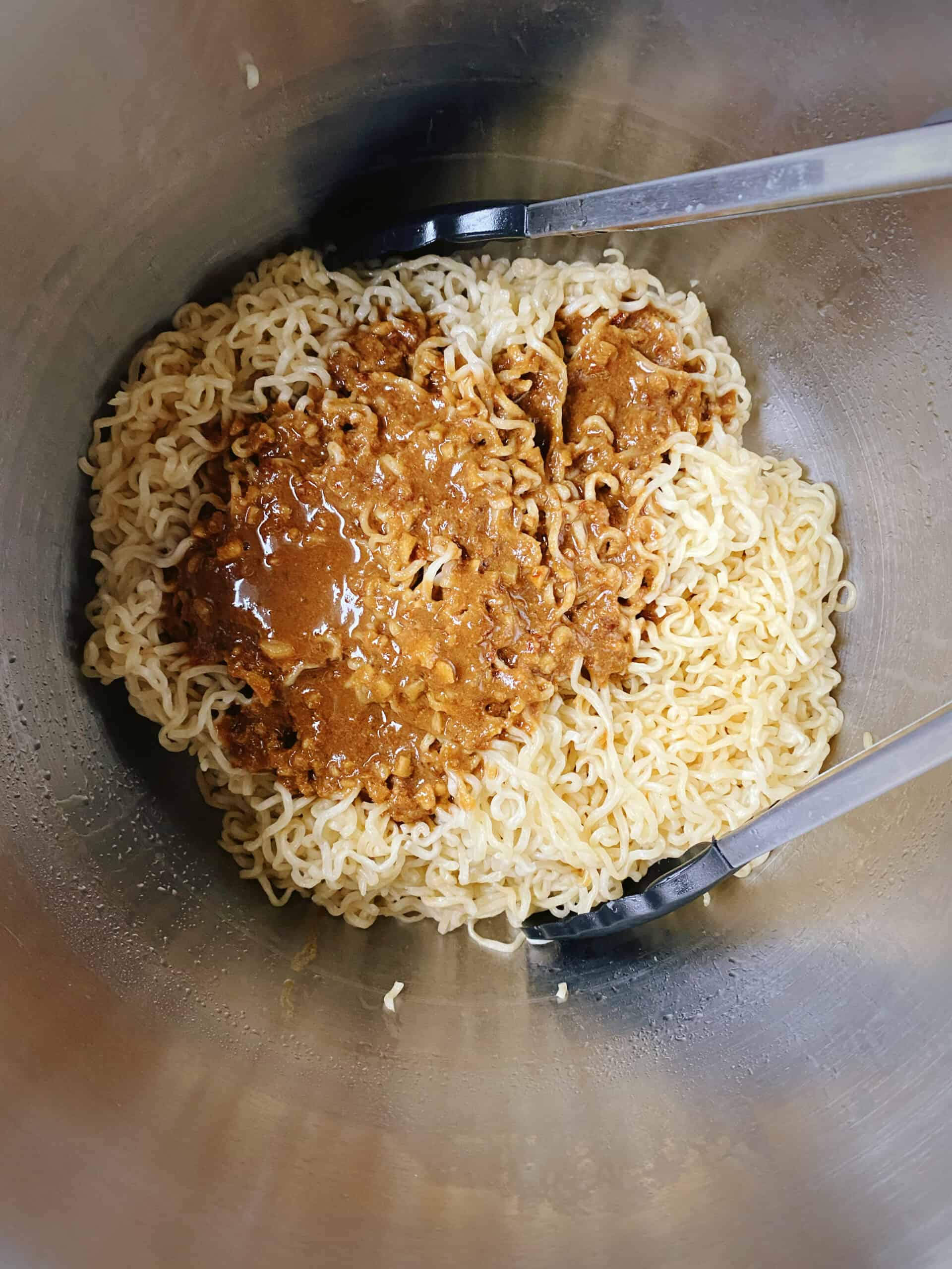 sesame ginger garlic peanut sauce added to drained noodles in the pot.