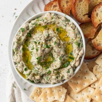 overhead shot of healthy, no-mayo tuna dip on a serving platter and topped with olive oil and fresh herbs.