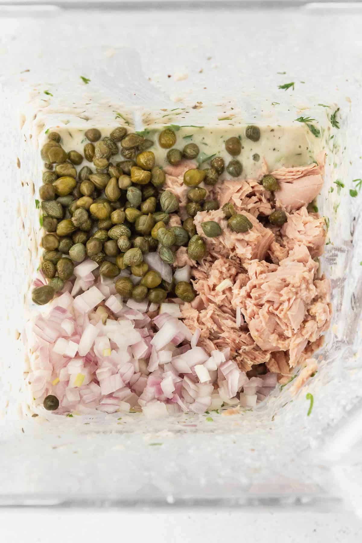 flaked tuna, capers, and shallots added to blender with herby bean purée to make tuna dip.