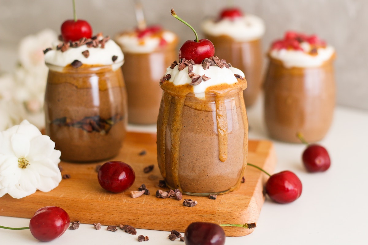 egg free chocolate budding in small cups garnished with fresh cherries.