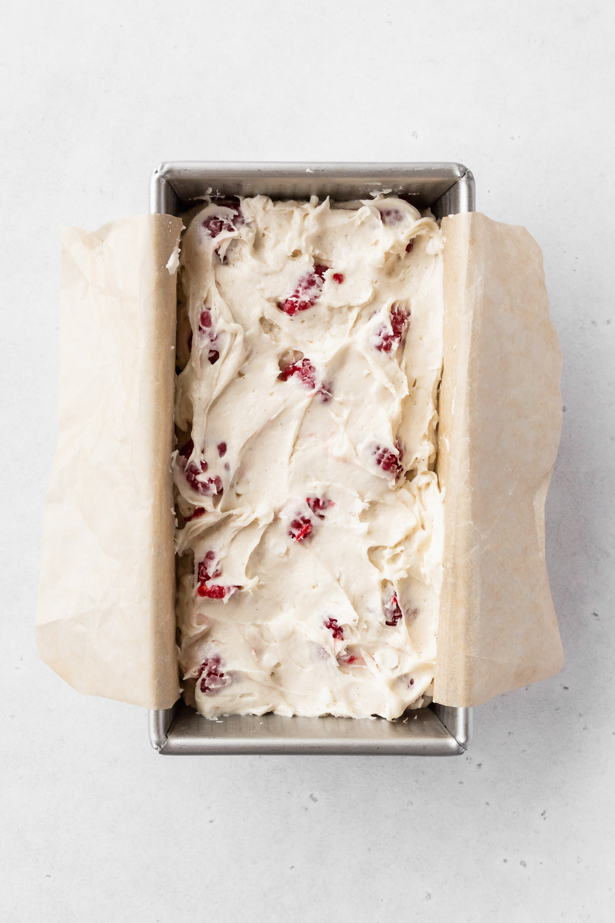 assembled egg-free raspberry white chocolate loaf cake in the baking tin before baking.