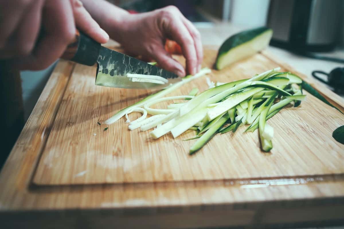 slicing a cucumber on a wooden cutting board. photo credit igor miske.