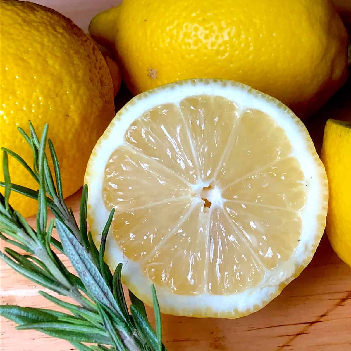 halved lemon and sprig of fresh rosemary on a wooden cutting board. photo credit mary khaliqi.