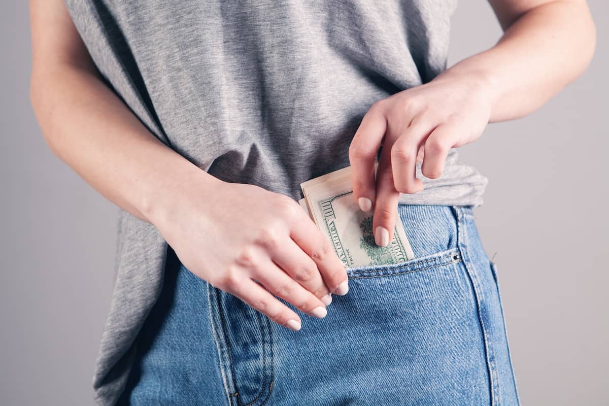 woman placing a wad of cash in her front pocket. Photo credit Sasun Bughdaryan.