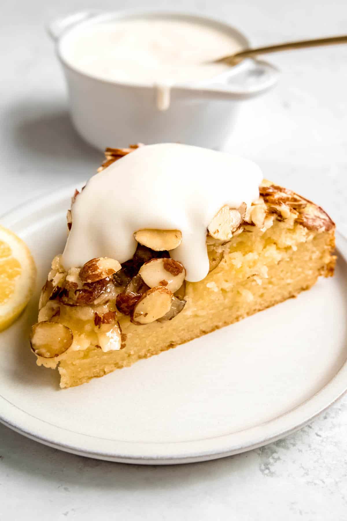 slice of Italian lemon almond cake on a white dessert plate topped with a dribble of whipped sweet ricotta.