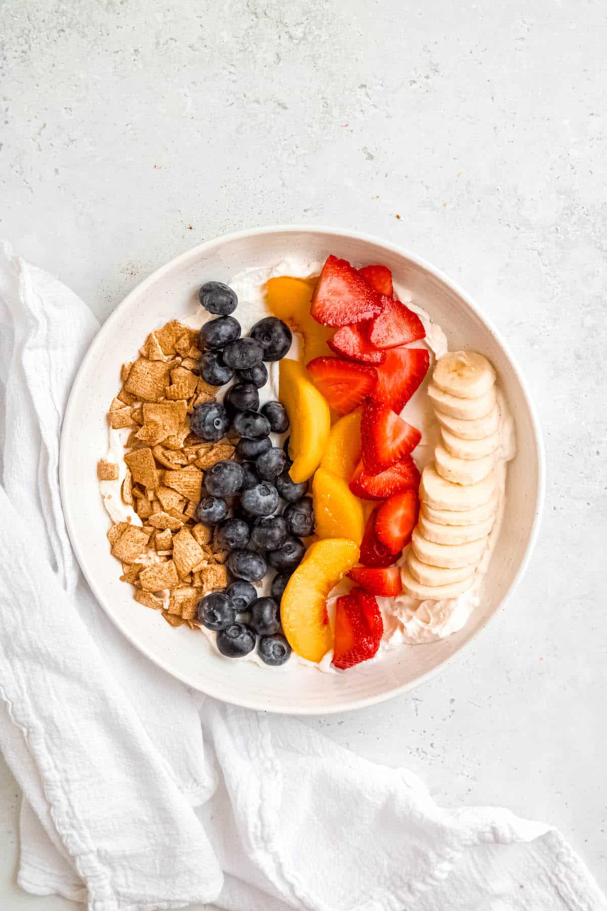 sliced bananas, strawberries, peaches, and blueberries added to the bowl.