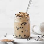 edible peanut butter cookie dough in a glass jar with a silver spoon.