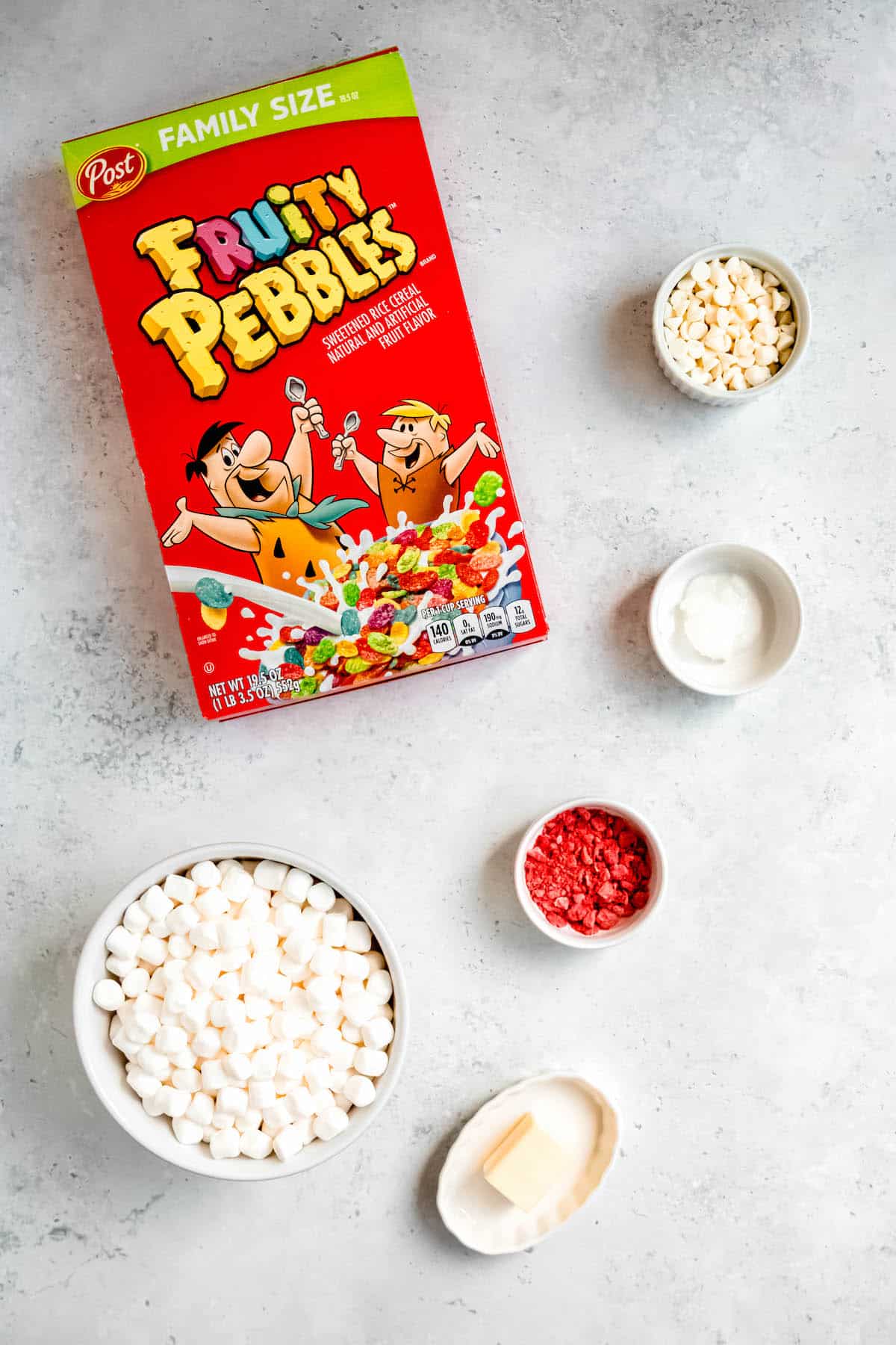 ingredients needed to make fruity pebbles cereal bars measured out onto a white table.