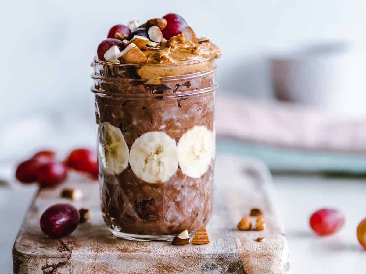 DIY overnight oats in a mason jar topped with nut butter and grapes.