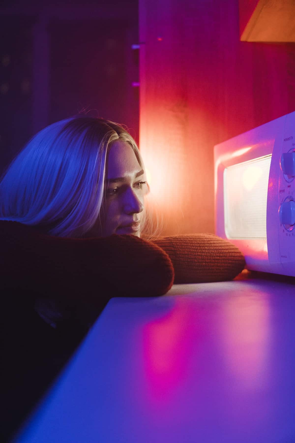 college student waiting for her microwave meal to finish cooking.