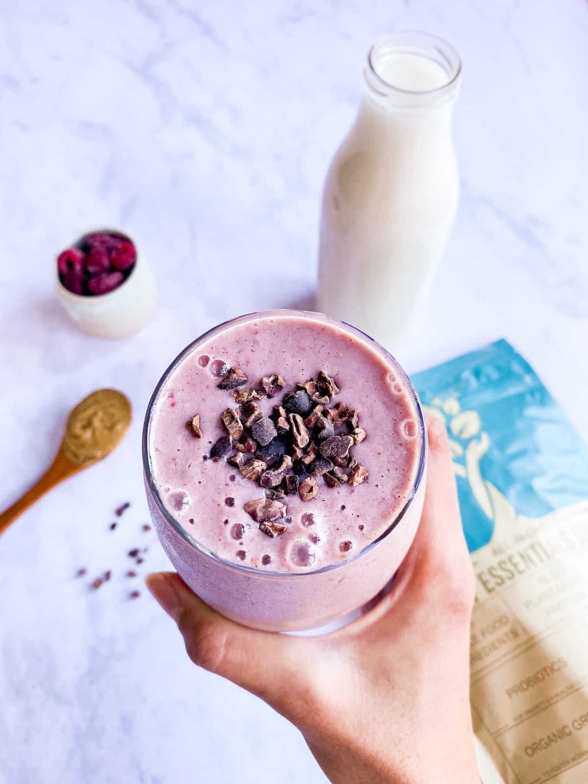 DIY frozen smoothie pack after blending into a smoothie with milk and topped with cacao nibs.