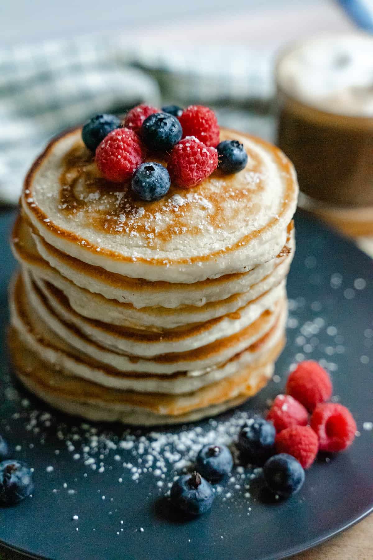 stack of DIY frozen pancakes plated in a stack with powdered sugar and berries.