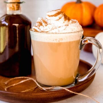 square hero image of a homemade pumpkin spice latte next to a stoppered jar of homemade starbucks pumpkin sauce.