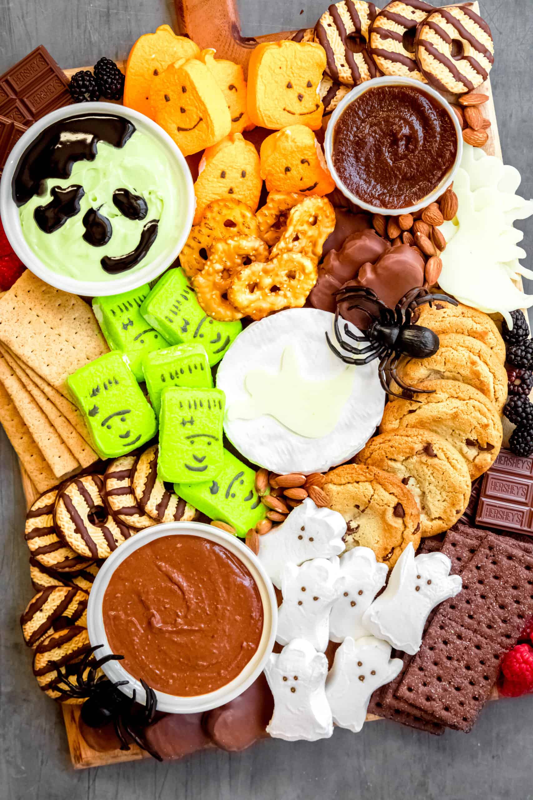 closeup overhead shot of halloween s'mores charcuterie board with dips, cheeses, berries, and s'more making supplies.