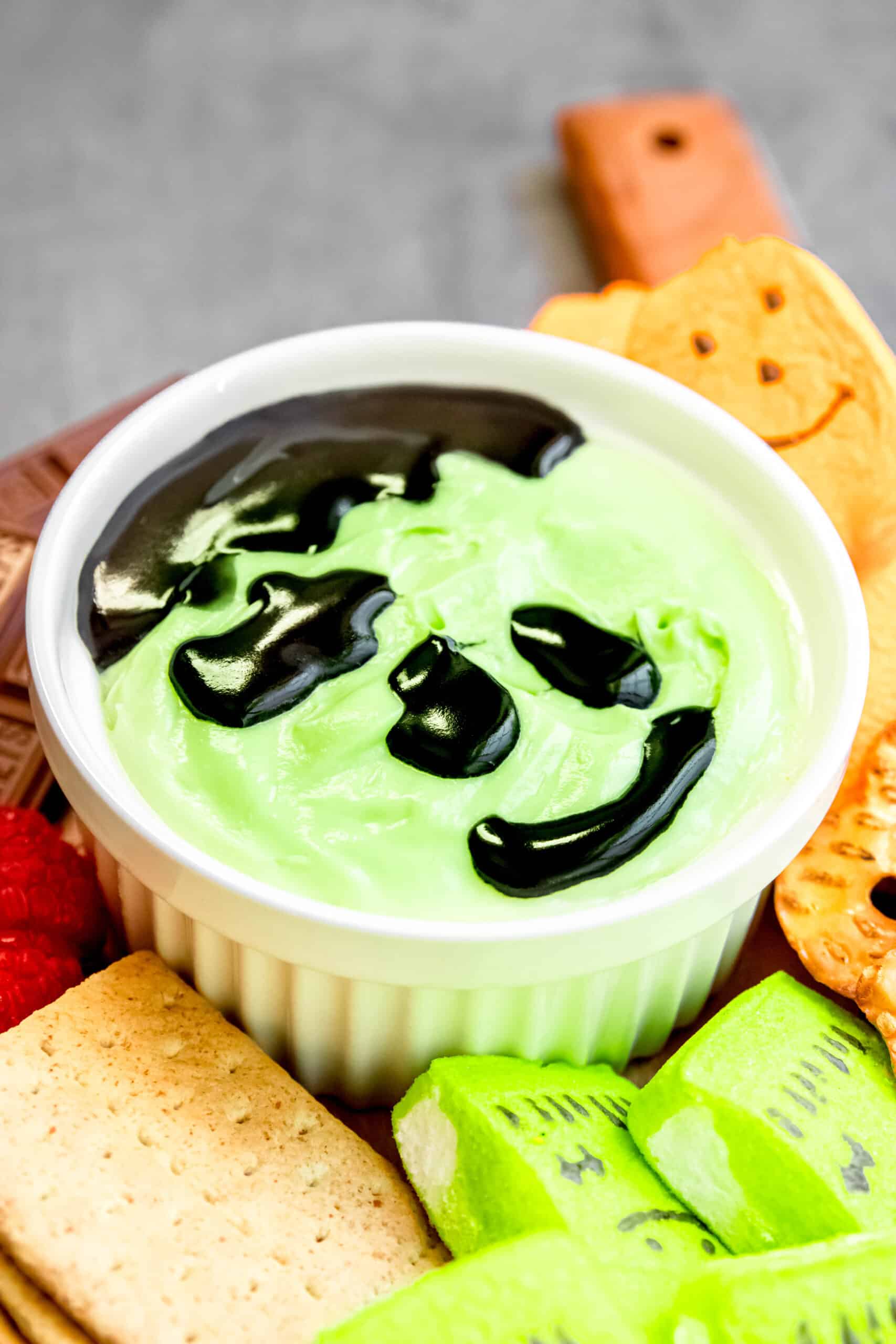 closeup on cream cheese fruit dip with a frankenstein face drawn on.