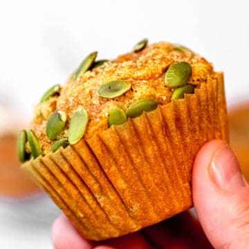 square hero image of a hand holding a banana pumpkin protein muffin.