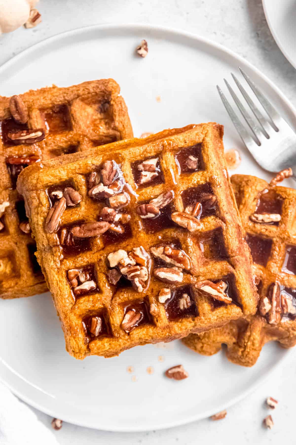 closeup shot of pumpkin pecan waffles topped with spiced pecan maple syrup.