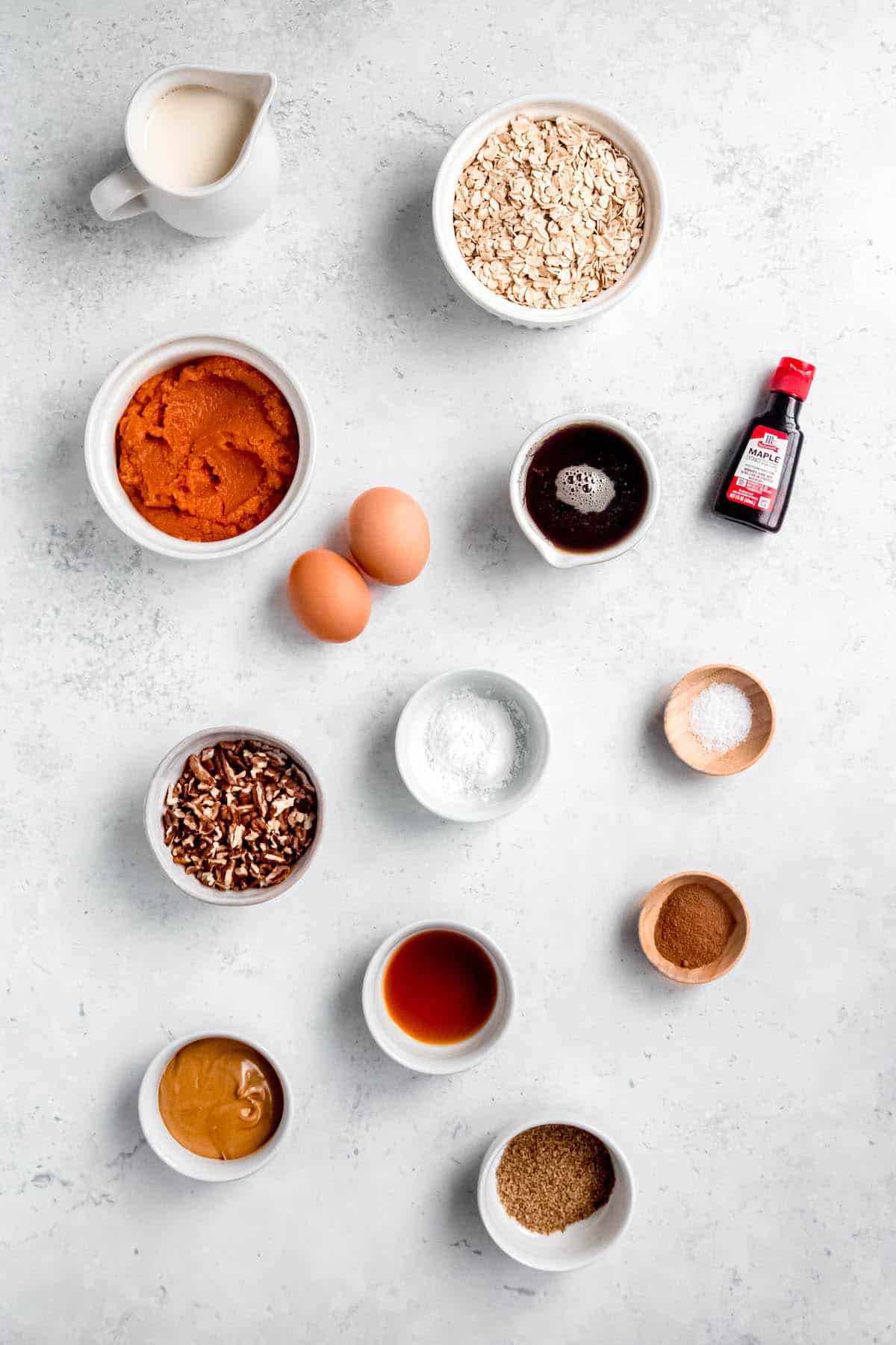 ingredients needed to make healthy pumpkin pecan waffles measured out into bowls on a white table.