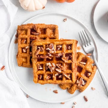 square hero image of gluten-free pumpkin pecan waffles on a plate.
