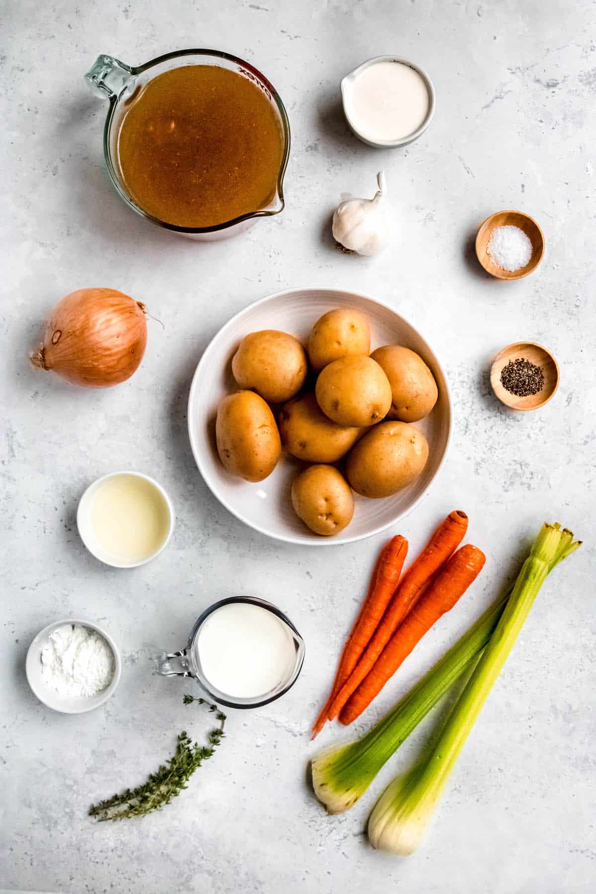ingredients needed to make gluten free instant pot potato soup measured out into bowls on a white table.