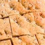 closeup shot of focaccia after slicing. you can clearly see flakes of maldon salt and coarse black peppercorn.