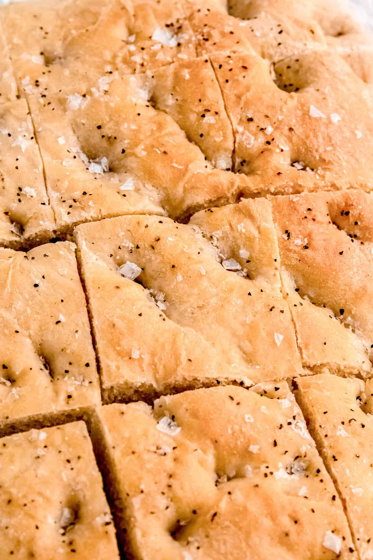 closeup shot of focaccia after slicing. you can clearly see flakes of maldon salt and coarse black peppercorn.
