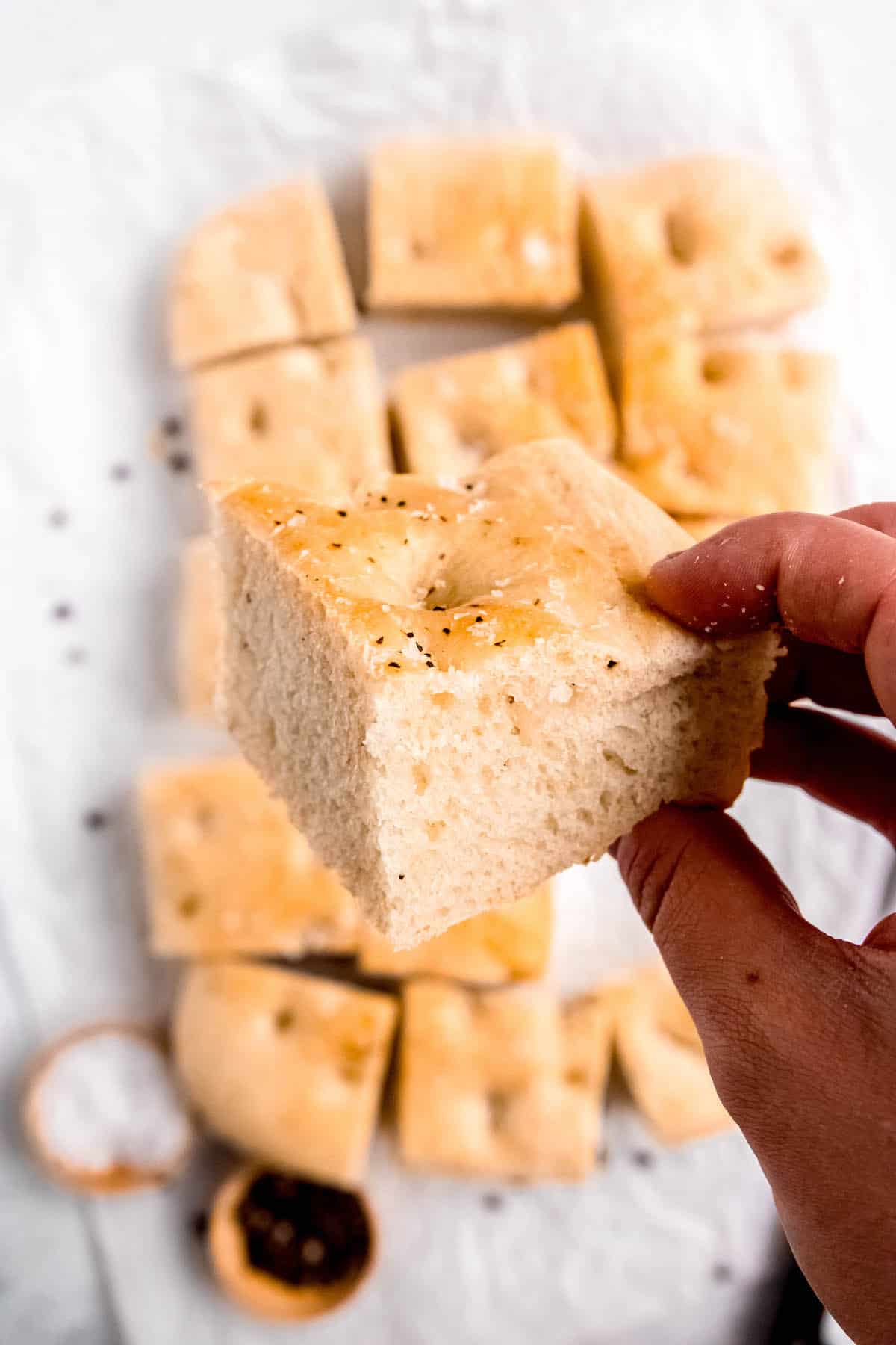 hand holding a slice of fluffy black pepper focaccia showing the airy texture inside.