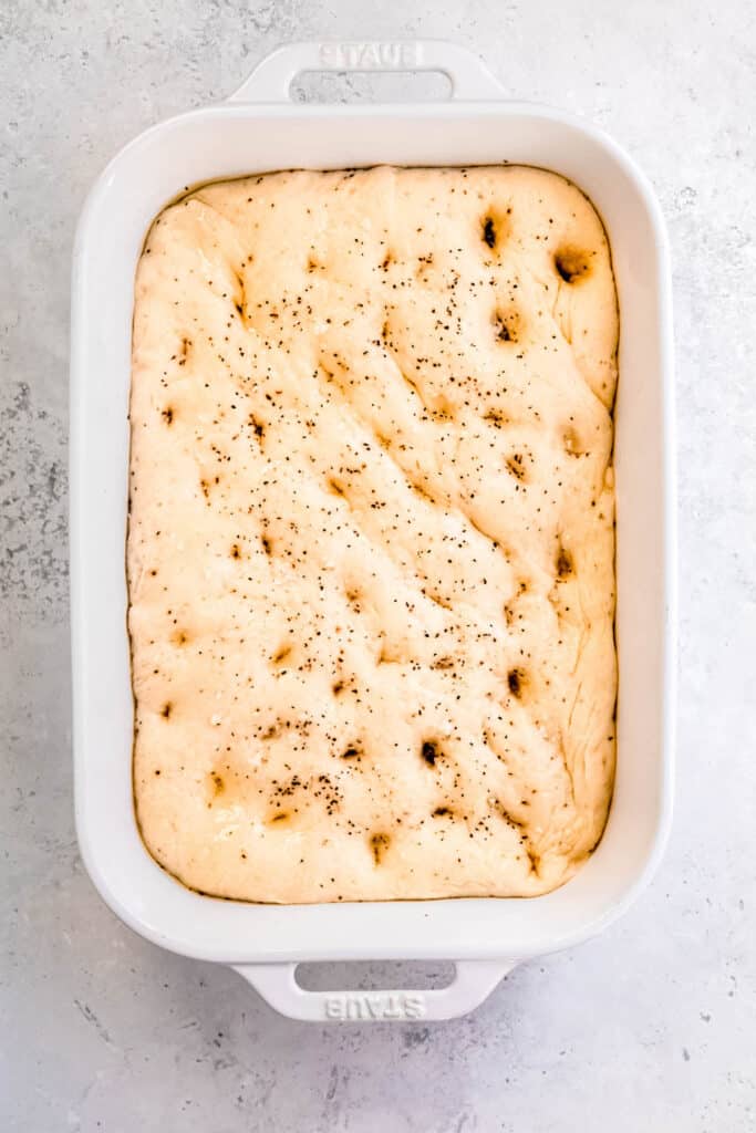 focaccia sprinkled with more olive oil, freshly cracked black pepper, and flaky sea salt before baking.