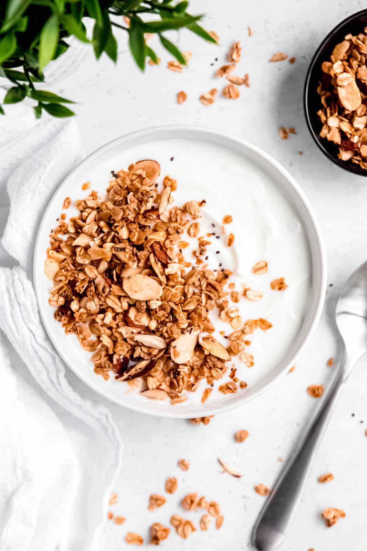 flat lay shot of a bowl of yogurt topped with homemade bulk granola with more of the almond vanilla granola to the side.
