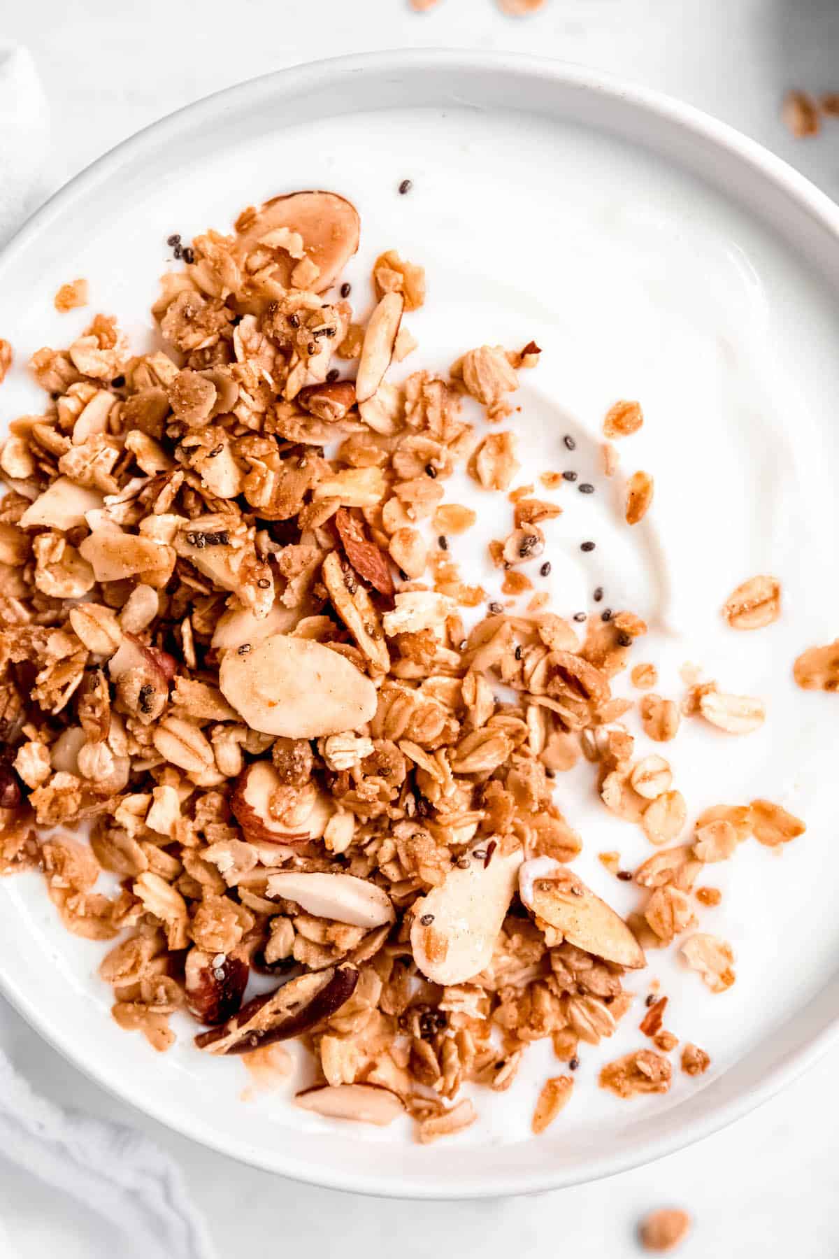 closeup flat-lay shot of a bowl of vanilla yogurt topped with homemade vanilla almond granola.