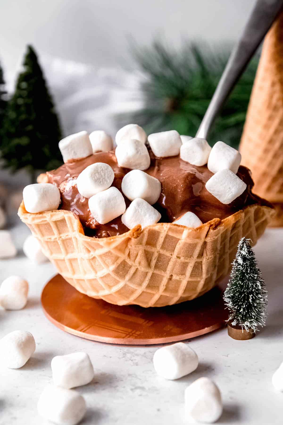 scoop of hot chocolate ice cream in a waffle bowl topped with extra marshmallows.