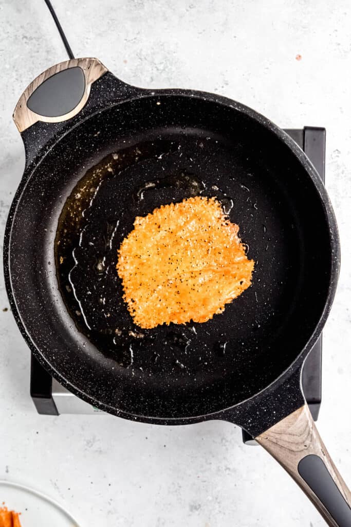 the gouda frico has been flipped over revealing a golden brown top.