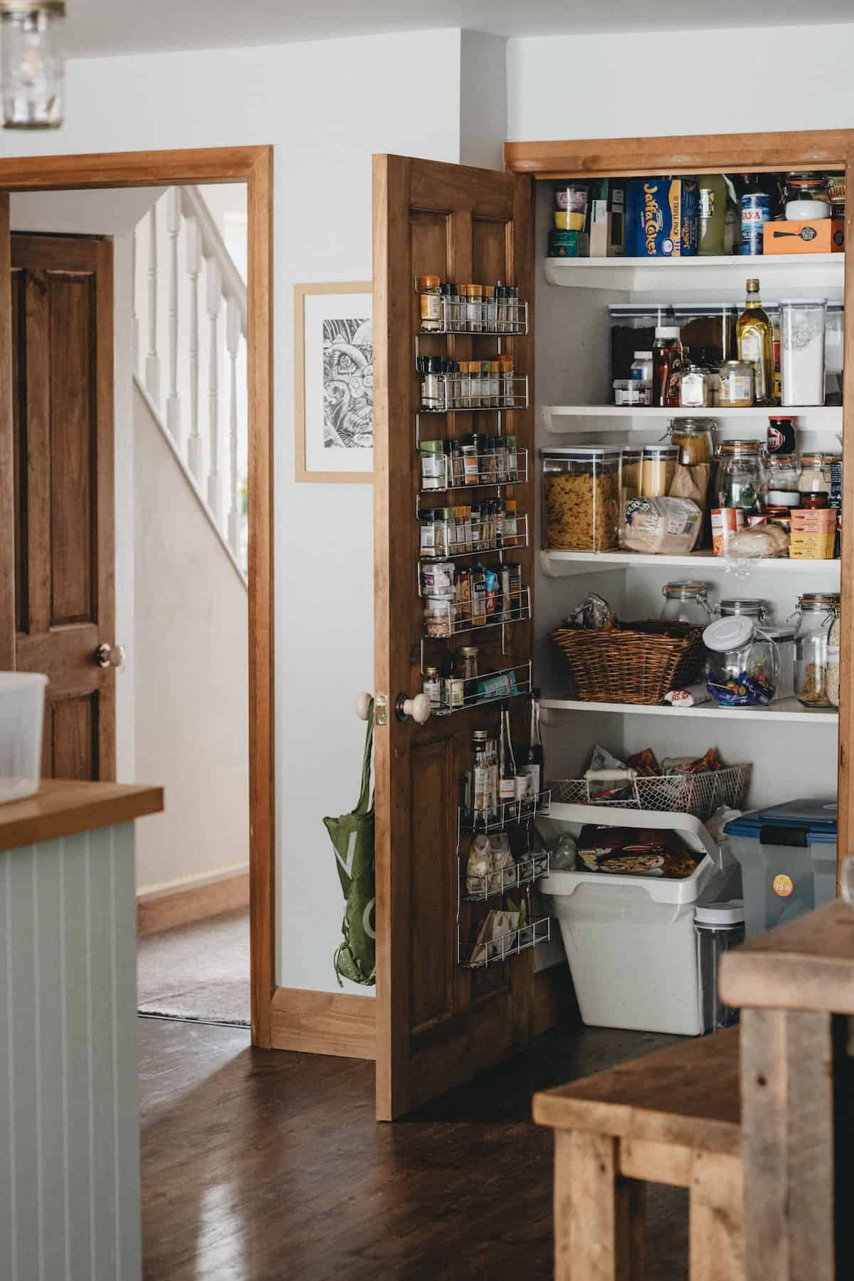 door to the pantry is open in a farmhouse style kitchen, revealing lots of dry ingredients to use for no-spend january.