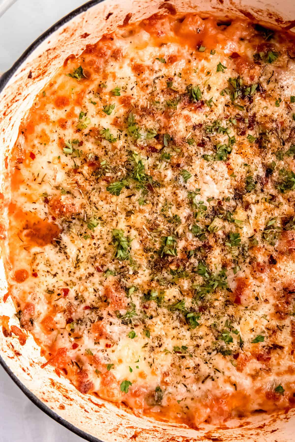 flat lay hero shot of a closeup on the Dutch oven filled with cheesy white bean tomato bake.