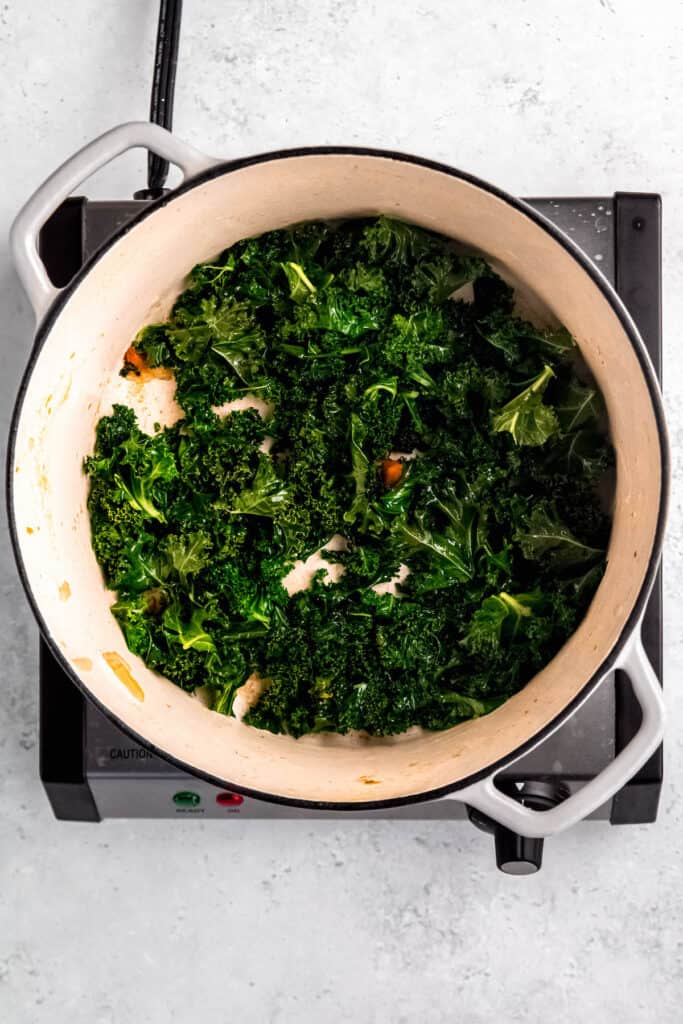 kale being sautéed in the empty dutch oven after draining the beans.