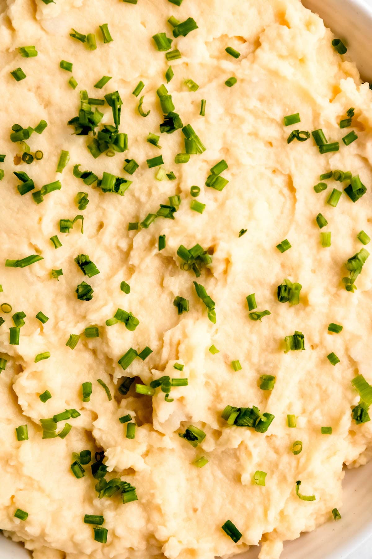 hyper closeup flat lay shot of greek yogurt mashed potatoes topped with chives, showing the creamy consistency.
