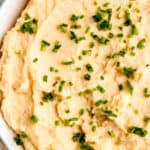 closeup overhead shot of a bowl of creamy mashed potatoes with greek yogurt topped with minced chives.