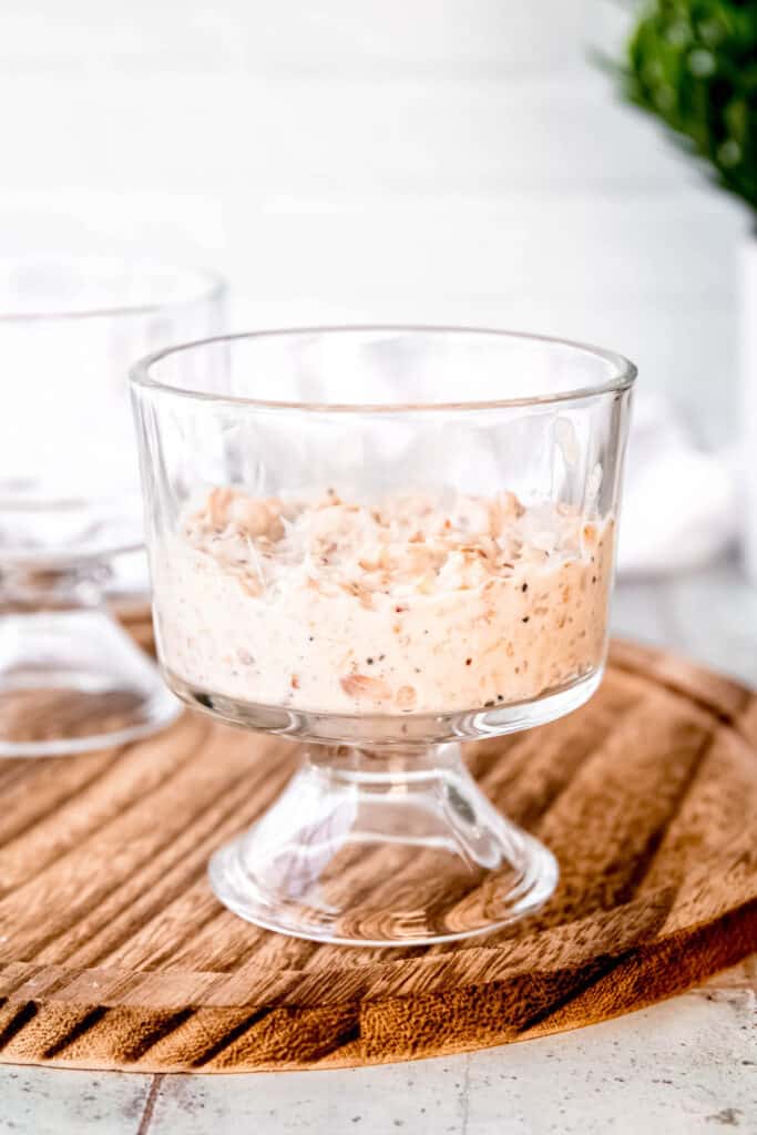 lemony cheesecake overnight oats spooned into the base of a small footed glass.