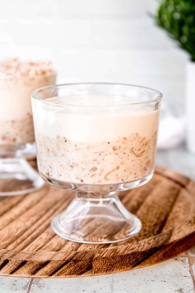 cottage cheese cheesecake layer spooned on top of the overnight oats in a small footed glass.