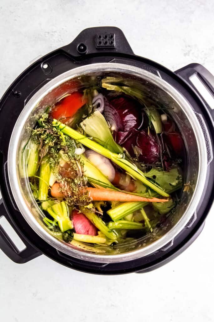 flat lay shot of vegetable scraps in an instant pot with water for making homemade sipping broth.