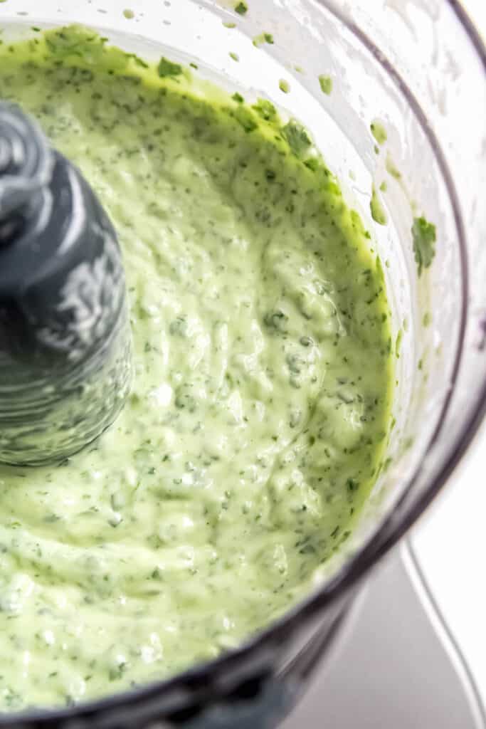 closeup shot of spicy, creamy cilantro lime dip in the food processor bowl.