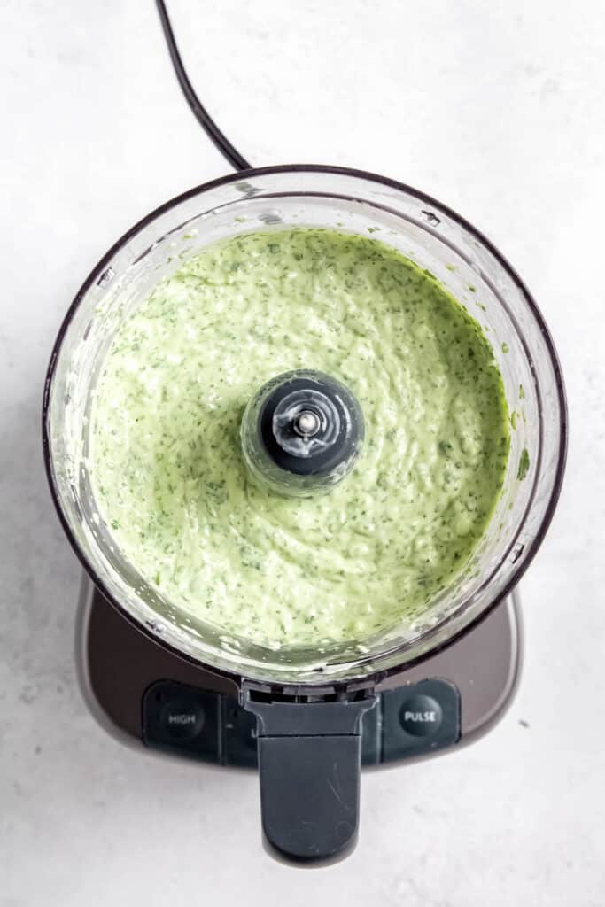 flat lay shot of the garlic cilantro sauce in the food processor after blitzing.