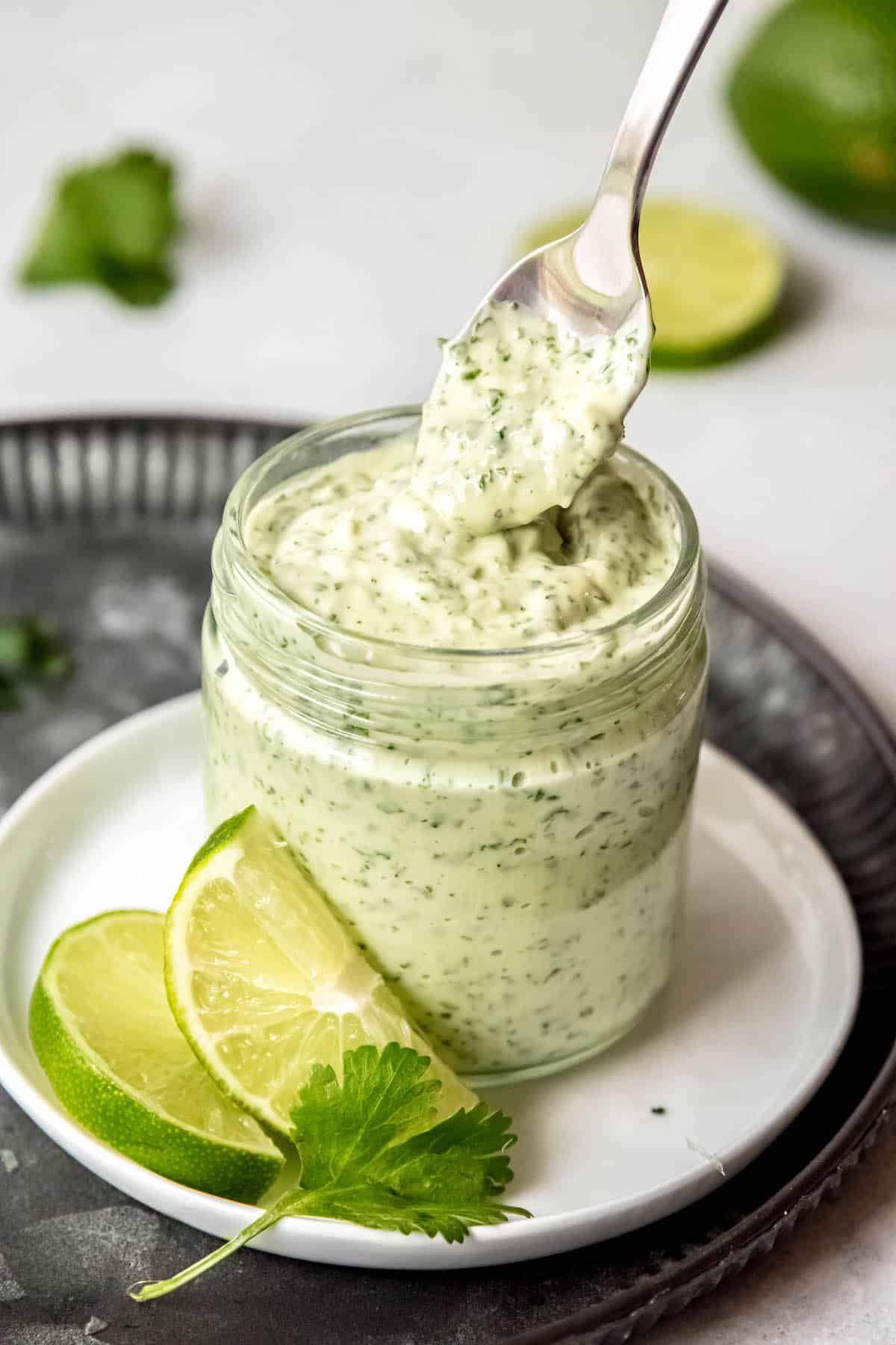 silver spoon taking a dollop of creamy cilantro garlic sauce out of the jar.