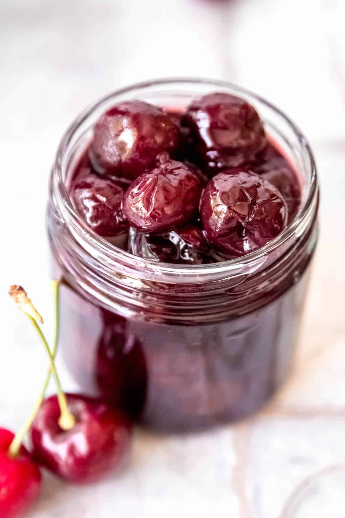 short glass jar filled with homemade Lazzaroni-style Italian cocktail cherries soaked in amaretto syrup.