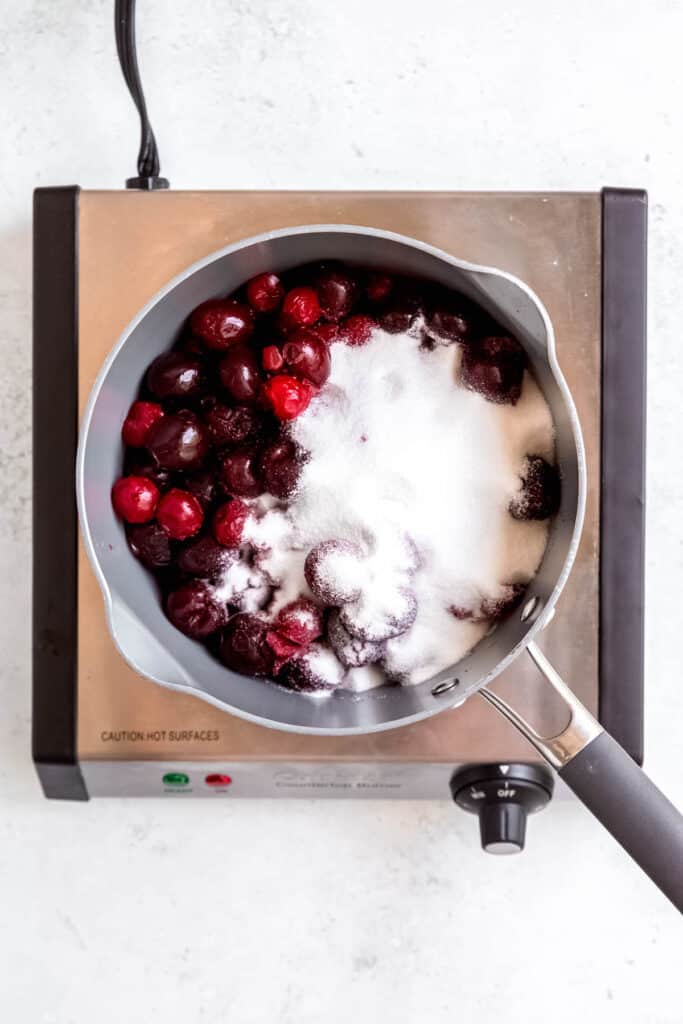 cherries and sugar in a silver saucepan.