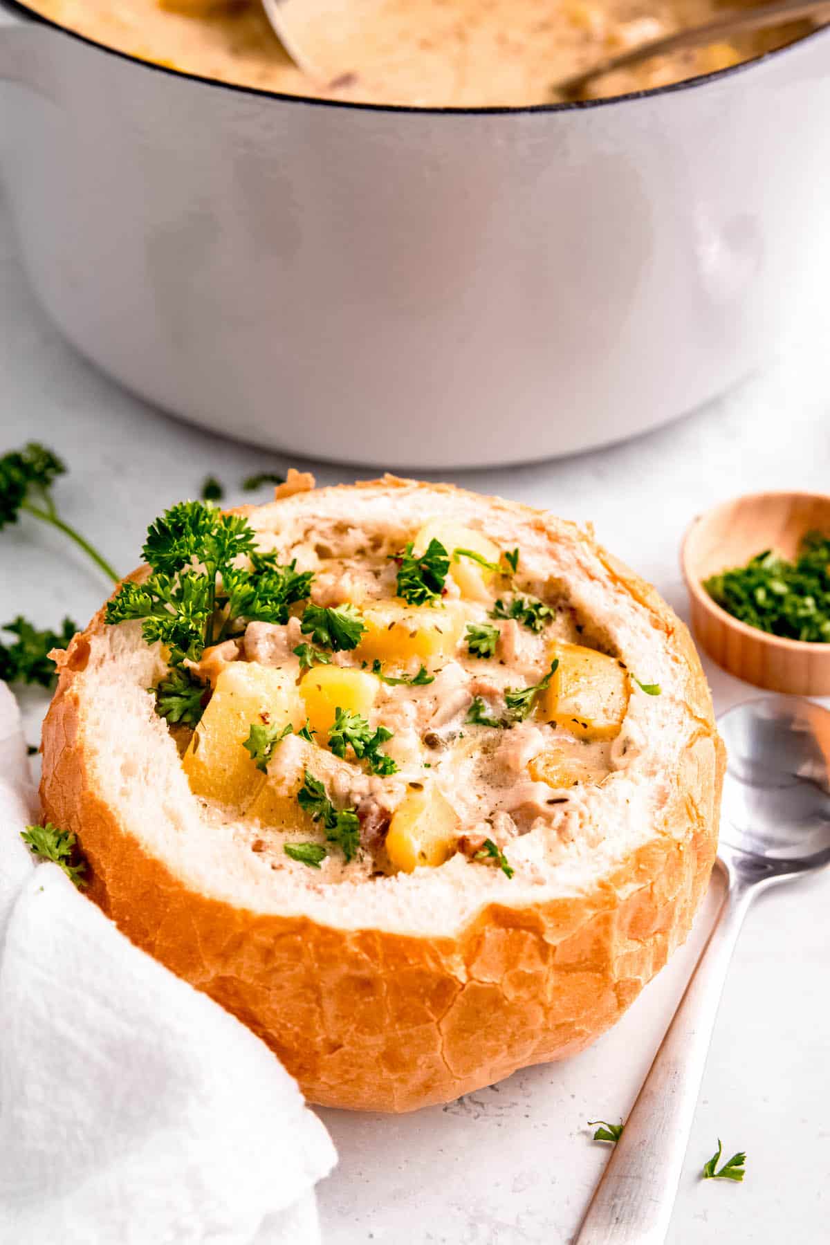 bread bowl filled with GF clam chowder with the pot of the rest of the soup in the background.